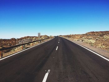 Empty road against clear blue sky