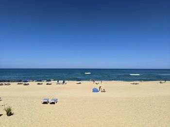 People at sandy beach against clear blue sky in hossegor, france. 