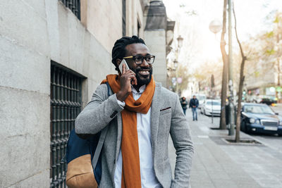 Businessman talking on phone while walking on sidewalk in city