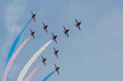 Low angle view of airplanes with trails in flight