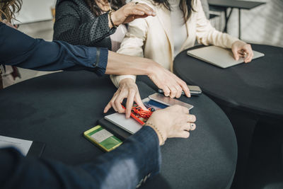 Midsection of female professionals taking their smart phones from table during conference event