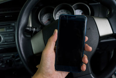 Close-up of hand using mobile phone in car