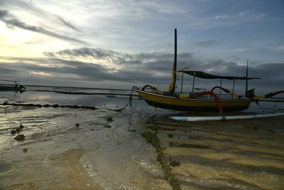 Boat moored at beach against sky