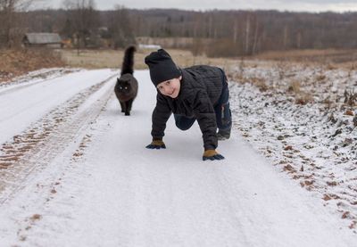 Full length of kid walking on snow covered road