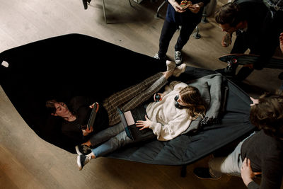 High angle view of businesswomen with laptop sitting on hammock in office