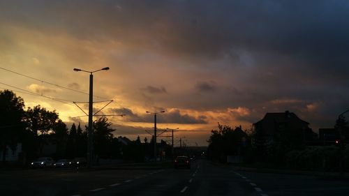 Cars on road against dramatic sky during sunset