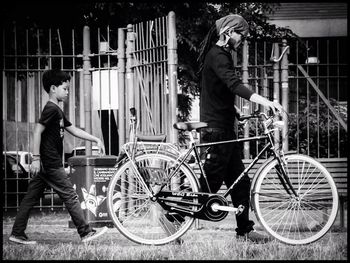 Full length of man and boy walking with bicycle