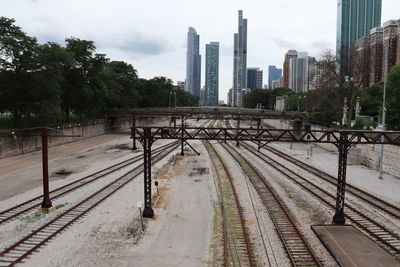 Railroad tracks by buildings in city against sky