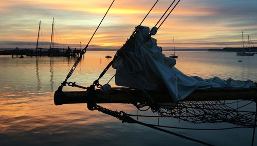 Nautical vessel moored on sea against sky during sunset
