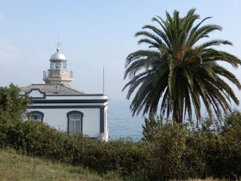 Palm trees and lighthouse at candás, asturias, spain against sky
