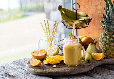 A homemade mango citrus smoothie on a rustic board against a window.