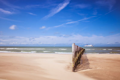 Wooden posts on beach against sky