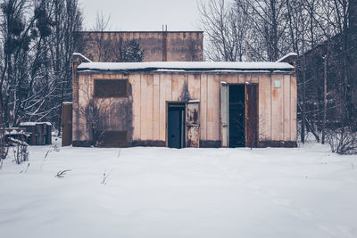 House and bare trees by building during winter