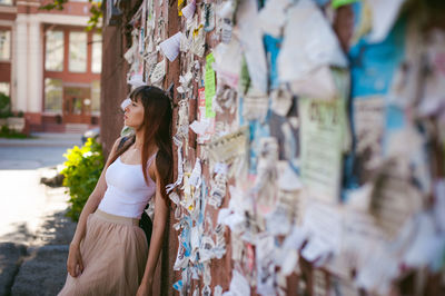 Young woman leaning on wall with torn posters