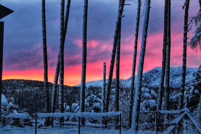 Snow covered landscape against sky during sunset