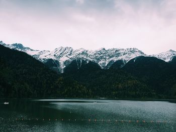 Scenic view of lake by snowcapped mountains against sky