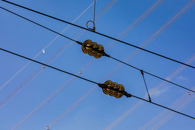 Black cables with insulators of a railroad line against blue sky