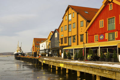 Boats moored at harbor against sky in city