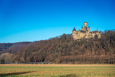 Built structure on landscape against clear blue sky