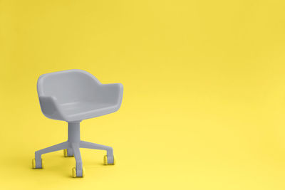 Close-up of empty chair against yellow background