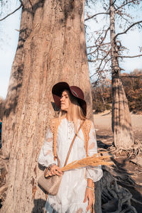 Woman standing by tree trunk