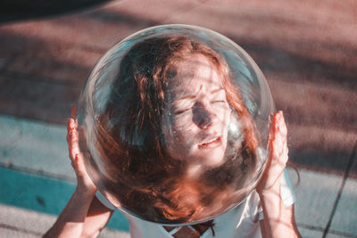 Close-up high angle view of young woman wearing glass helmet in head during sunny day