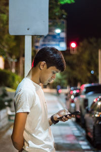 Side view of young man looking at city street
