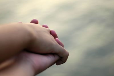 Cropped image of two people holding hands outdoors