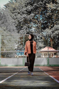 Full length of young woman standing against trees