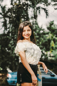 Portrait of smiling girl standing against trees