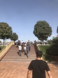 Rear view of people walking on road against clear sky