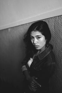 High angle portrait of young woman standing on steps against wall