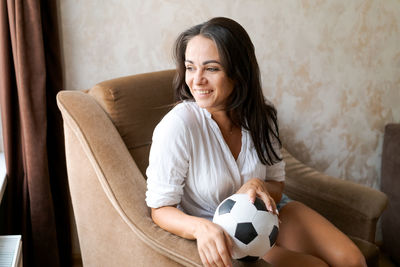 Woman sitting on a chair holding a soccer ball in her hand