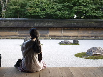 Rear view of a woman sitting on riverbank