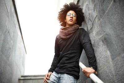 Low angle view of young man standing on steps against clear sky