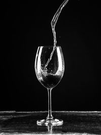 Close-up of wineglass on table against black background