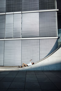 Businessman taking selfie through smart phone lying on wall in front of modern building