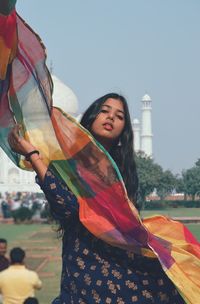 Portrait of smiling young woman standing against taj mahal