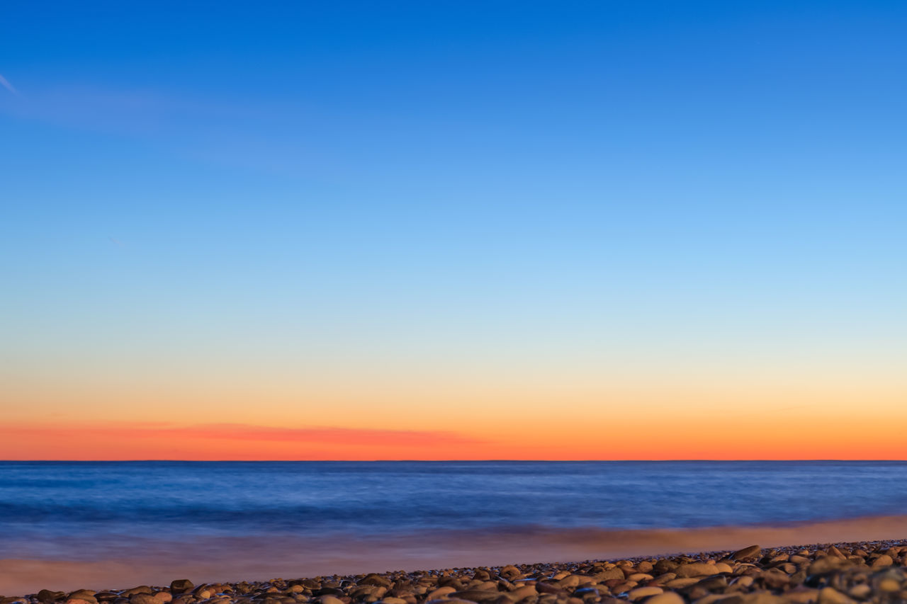 SCENIC VIEW OF SEA AGAINST CLEAR BLUE SKY DURING SUNSET