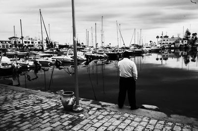 Rear view of man standing at harbor