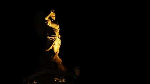 Low angle view of illuminated statue against black background