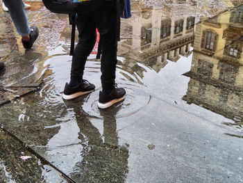 Low section of man standing on puddle