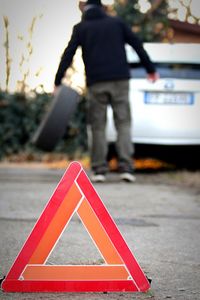 Rear view of man standing on road sign wheel changing