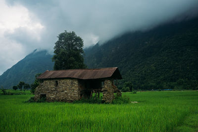 Built structure on field by mountain against sky