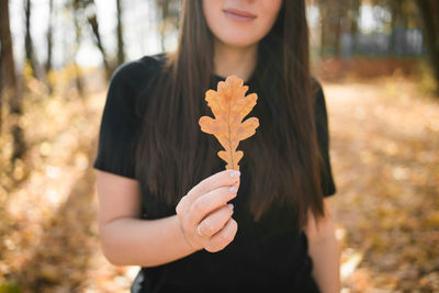 Midsection of woman holding autumn leaf