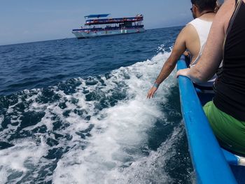 Rear view of people on sea against sky