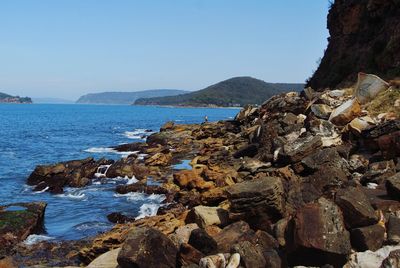 Scenic view of sea and mountains against clear blue sky