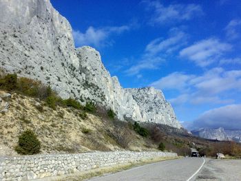 Country road leading towards mountains against blue sky