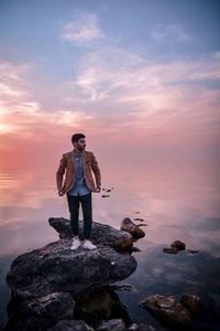 Full length of man standing on rock against sea