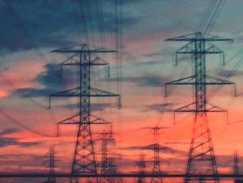 Low angle view of silhouette electricity pylon against sky during sunset